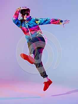 Boy dancing in neon light studio. Acrobatic dancer. Stylish flex.