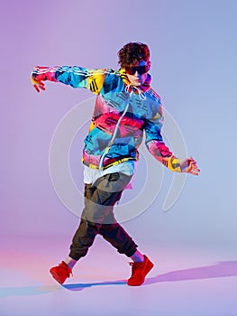 Boy dancing in neon light studio. Acrobatic dancer. Stylish flex.