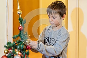 The boy decorates the Christmas tree. Children in Xmas