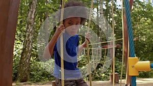 Boy deftly moves along the hinged rope path on playground, grabbing the ropes