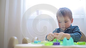 A boy in a denim shirt builds sand castles and fortresses