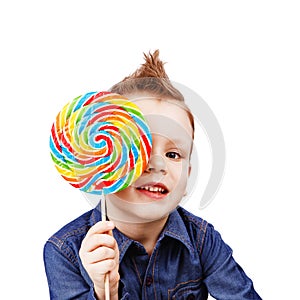 A boy in a denim shirt eating lollipop