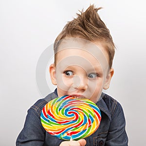 A boy in a denim shirt eating lollipop