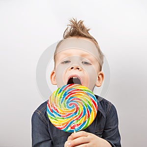 A boy in a denim shirt eating lollipop.