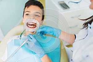 Boy in a dental cabinet, caries removal procedure