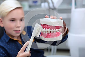 A boy at a dentist`s appointment learns to brush his teeth correctly. Portrait of a boy in a dental office. A toothbrush and a