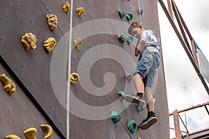 A boy descends on a rope on a climbing wall in a sports park climbing wall