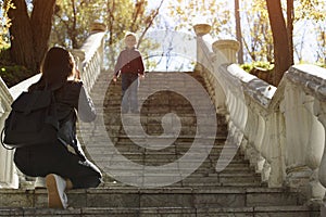 Boy descends stairs to his mother. Walk with baby in park. Naughty child