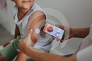 Boy with diabetes checking blood glucose level at home using continuous glucose monitor.