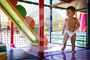 Boy in diaper with ball playing in playroom on weekend