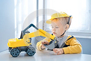 Boy with digger. Child play with excavator at home, dreams to be an engineer. Little builder. Education, and imagination