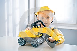 Boy with digger. Child play with excavator at home, dreams to be an engineer. Little builder. Education, and imagination
