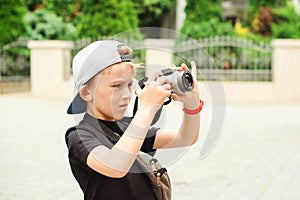 Boy with a digital camera taking pictures. School project for kids. Future profession. Summer holidays, memories and impressions