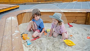 Boy digs sand with rake spending time with sister