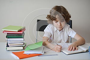 Boy diligently does his homework sitting at a school desk
