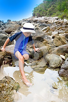 Boy dipping his toes in a rockpool photo