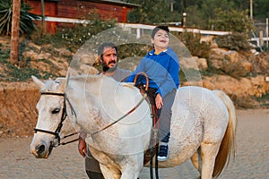 Boy with disabilities enjoying the experience of riding a horse at an equestrian center.