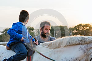 Boy with disabilities enjoying riding a horse outdoors at an equestrian center.