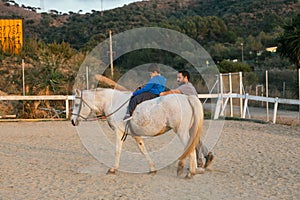 Boy with disabilities having an equine therapy session at equestrian center.