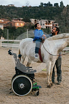 Boy with disabilities sitting on a horse while having his equine therapy.