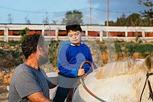 Boy with a disability riding a horse during an assisted equine therapy session.