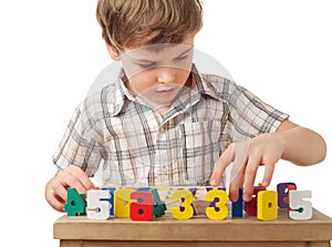 Boy displays wooden figures in form of numerals