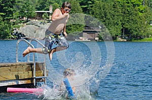Boy dive bombing friend off dock into lake photo