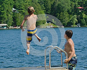 Boy dive bombing off dock into lake photo