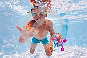 Boy dive in the pool collecting toys wear googles photo