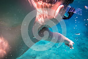 Boy dive in the sea and pointing to fish