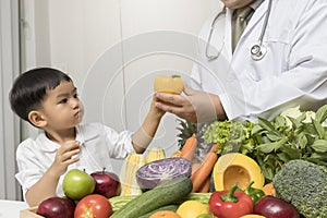 A boy and doctor happy to have healthy food. Kid learning about nutrition with doctor to choose eating fresh fruits and vegetables