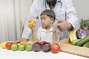 A boy and doctor happy to have healthy food. Kid learning about nutrition with doctor to choose eating fresh fruits and vegetables