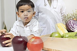 A boy and doctor happy to have healthy food. Kid learning about nutrition with doctor to choose eating fresh fruits and vegetables