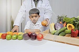 A boy and doctor happy to have healthy food. Kid learning about nutrition with doctor to choose eating fresh fruits and vegetables