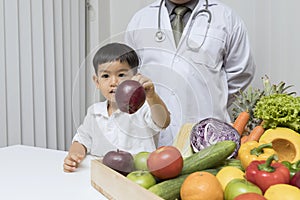 A boy and doctor happy to have healthy food. Kid learning about nutrition with doctor to choose eating fresh fruits and vegetables