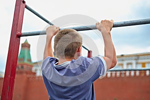 Boy does chin-ups against kremlin wall