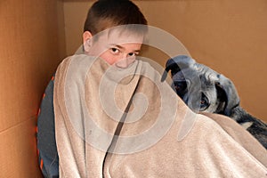 Boy and dog cuddling in a box