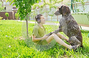Boy with a dog sitting on grass. Best friends. Happy moments. Listen to music. Earphones listening.