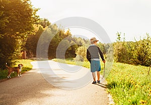Boy and dog walk on contryside road at the evening summertime photo