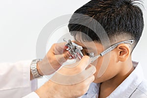 Boy doing eye test checking examination with optometrist in optical shop, Optometrist doing sight testing for child patient in