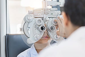 Boy doing eye test checking examination with optometrist in optical shop, Optometrist doing sight testing for child patient in photo