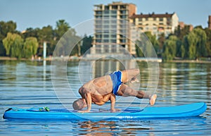 Boy doing handstanding position on paddle board during hot summer day.