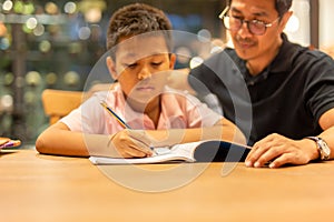 Boy doing homework with father at home.