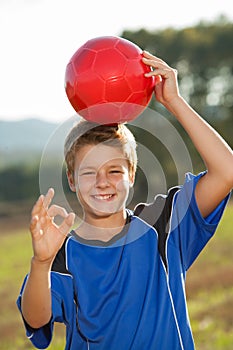 Boy doing okay sign with soccer ball.