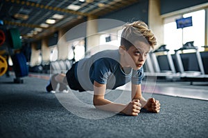 Boy doing push up exercise on the floor in gym