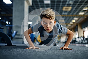 Boy doing push up exercise in gym, front view