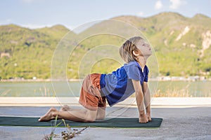 Boy doing yoga on a yoga mat against a background of mountains