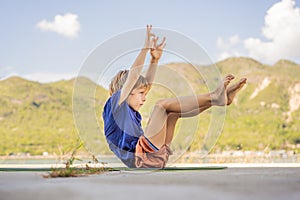 Boy doing yoga on a yoga mat against a background of mountains