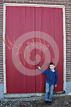 Boy by doors with graffiti