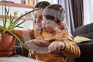 Boy with Down syndrome bonding to his lovely mother while she holding him at the hands